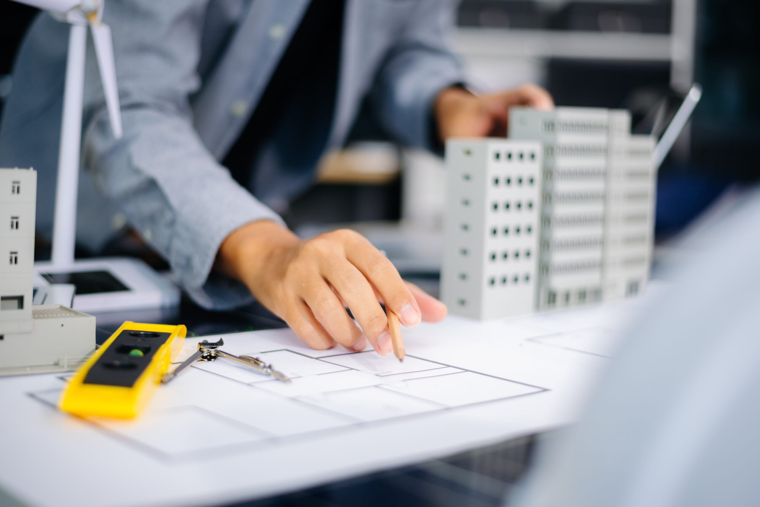 Architect drawing building plans next to scale models