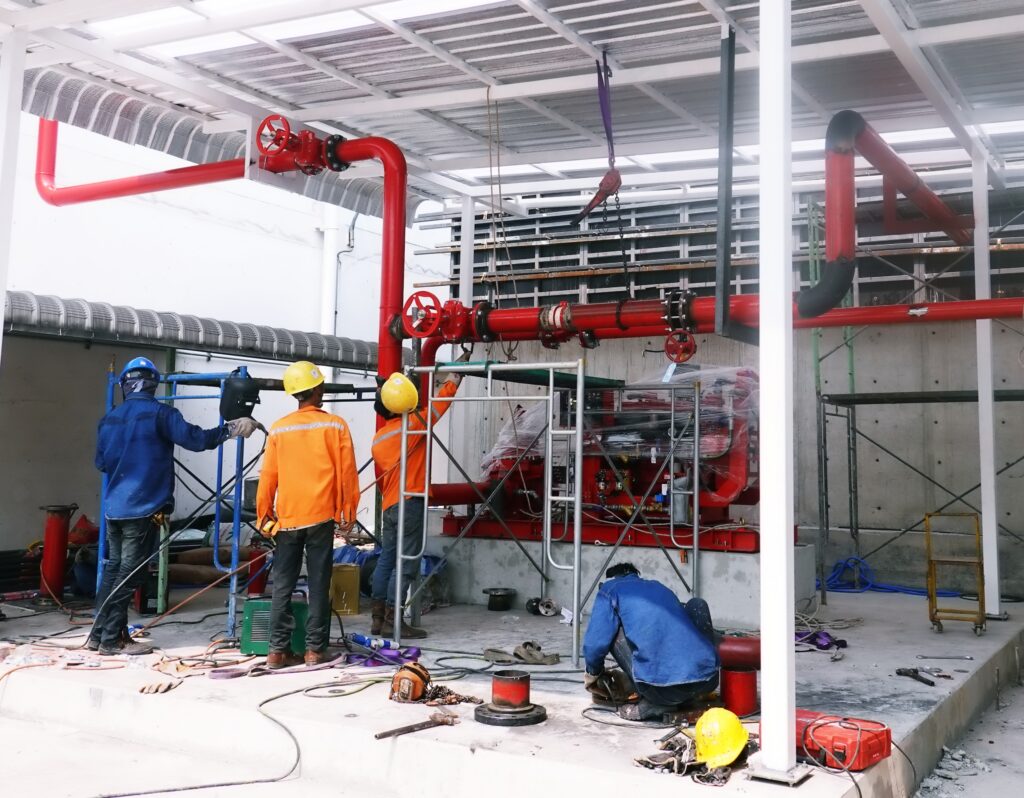 Workers installing red fire sprinkler piping