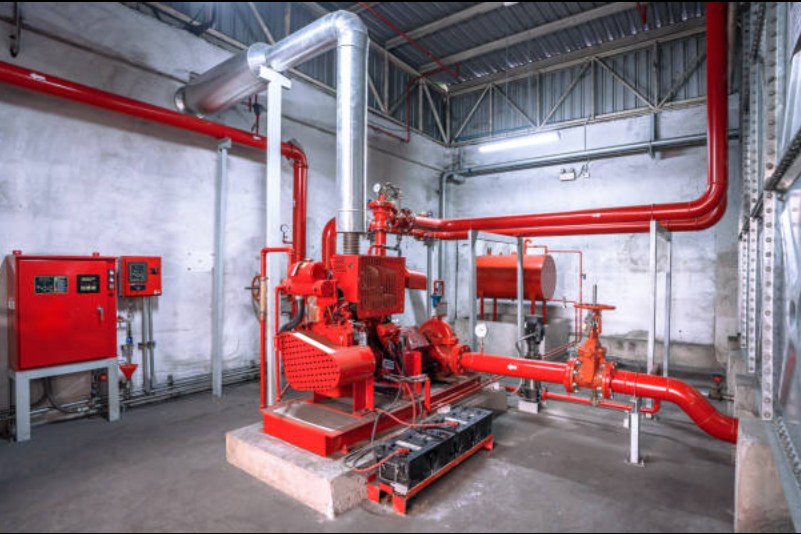 Diesel fire pump with red piping and controllers in a pump room