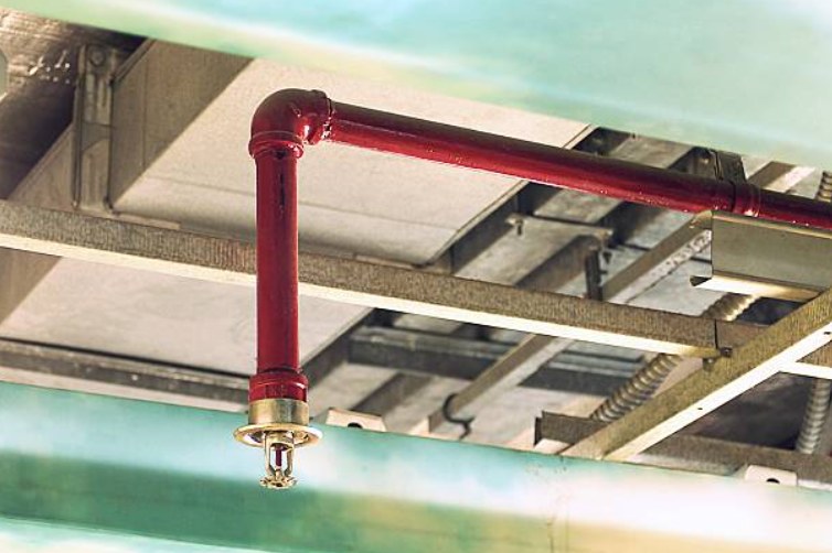 Red fire sprinkler pipe with pendant sprinkler head installed in a ceiling